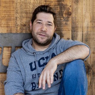 Portrait of Dennis Ramin in front of a wooden wall